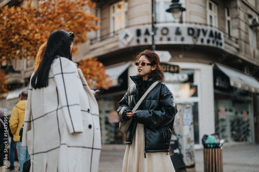 Obraz premium Two women interact outdoors in an urban setting surrounded by vibrant autumn scenery.