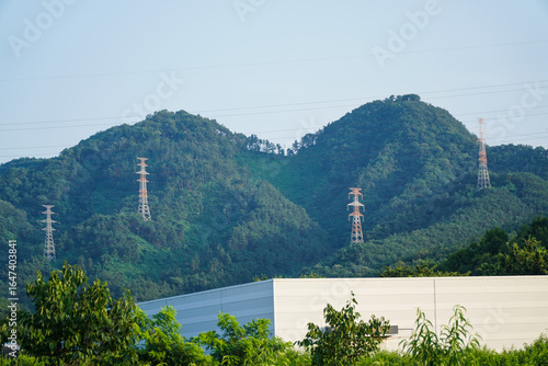 Power Lines and Transmission Towers Over Green Mountains