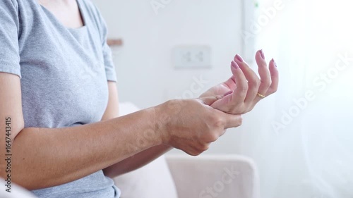 woman experiencing wrist pain, hand numbness, and tingling, symptoms of Carpal Tunnel Syndrome, holding and massaging her aching joint,  chronic hand injury, nerve compression, and repetitive strain
