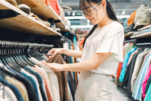 Canvastavla Young adult woman choosing used clothing at second hand clothes shop