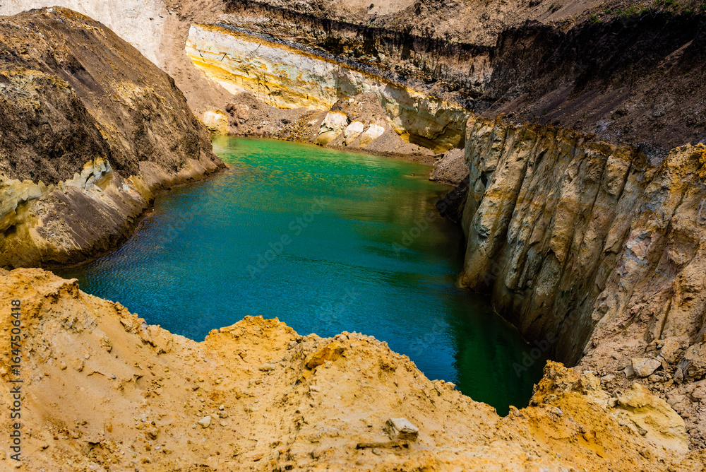 Fototapeta premium Sand quarry filled with water reflecting the cloudy sky, creating an industrial yet natural landscape