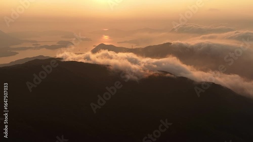 Wallpaper Mural Aerial view of sunrise over misty mountains and islands in Hong Kong, golden sunlight reflecting on the sea, dramatic clouds flowing across forested peaks in serene landscape Torontodigital.ca