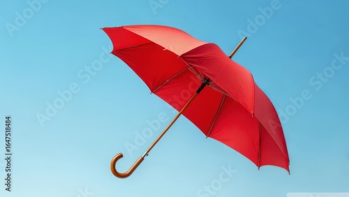 Red umbrella floating in a clear blue sky
