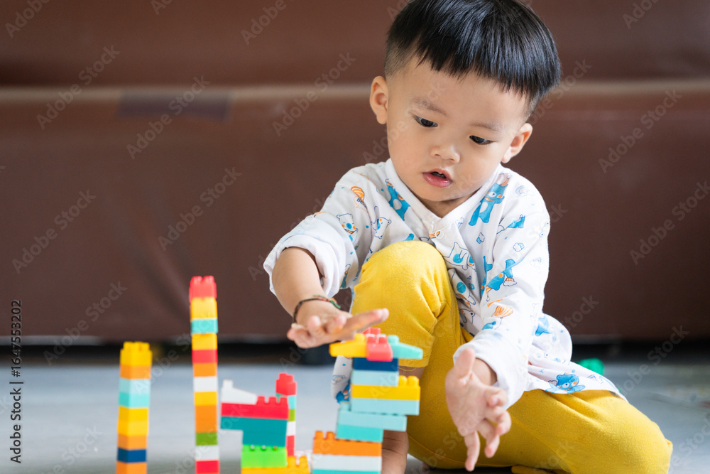 Fototapeta premium Child Playing with Colorful Building Blocks Indoors