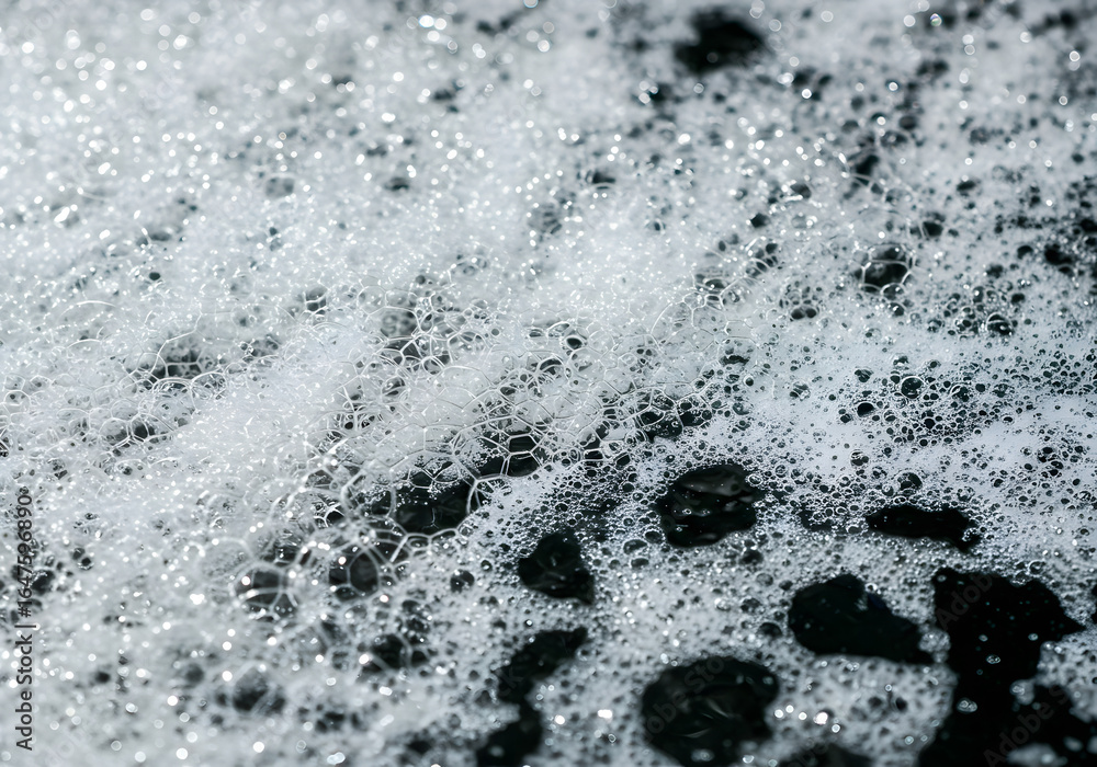 Obraz premium Close-up shot of white foam with bubbles against a dark background, creating a textured and abstract pattern.