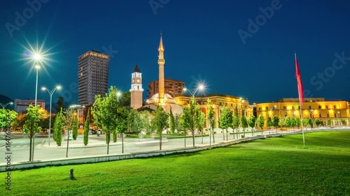 Cityscape at night with illuminated buildings, trees, and a clear sky in tirana
