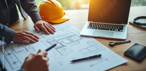 Architects and engineers meeting, a team gathers around blueprints with a laptop and hard hat, illustrating collaborative design, planning, and project development.