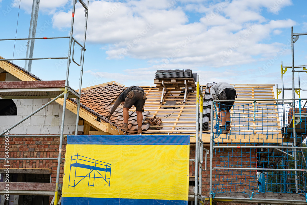 Naklejka premium Wohnhausbau - Dachdeckerarbeiten beim Eindecken eines neuen Einfamilienhauses.