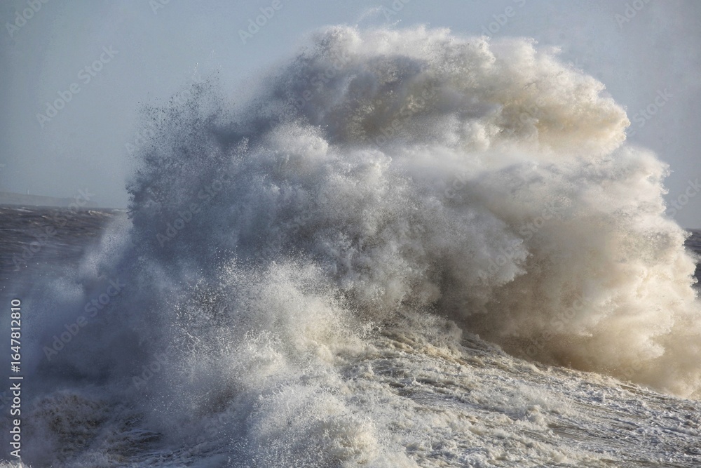 Obraz premium Giant waves hitting the sea wall and lighthouse at Porthcawl.