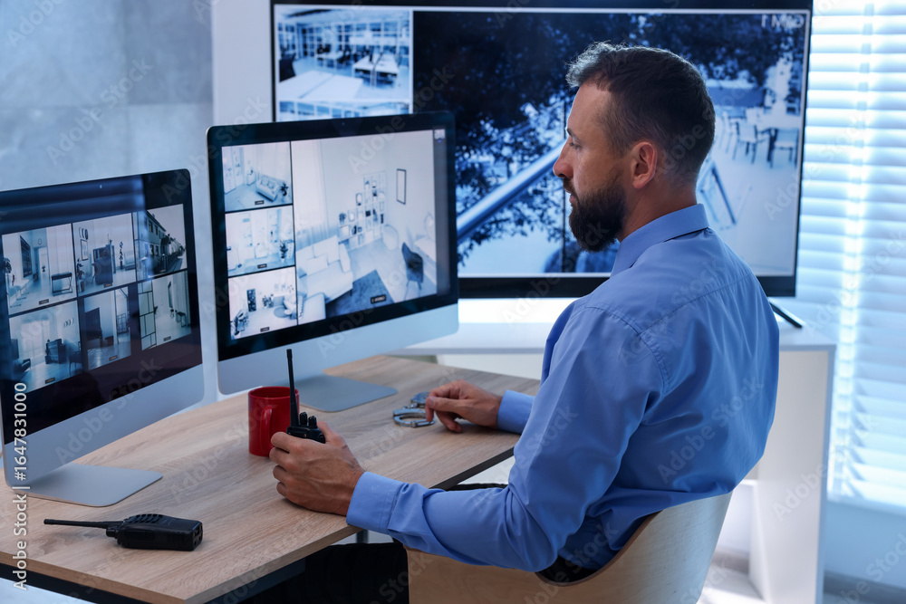 Fototapeta premium Security guard monitoring CCTV cameras in office
