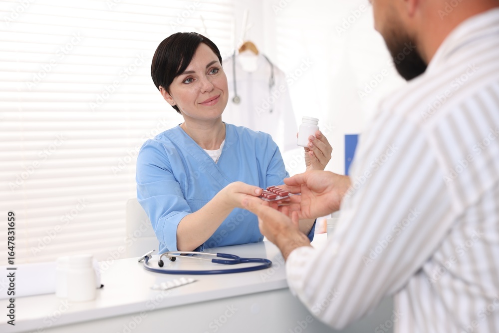 Fototapeta premium Gastroenterologist giving pills to patient at table in clinic