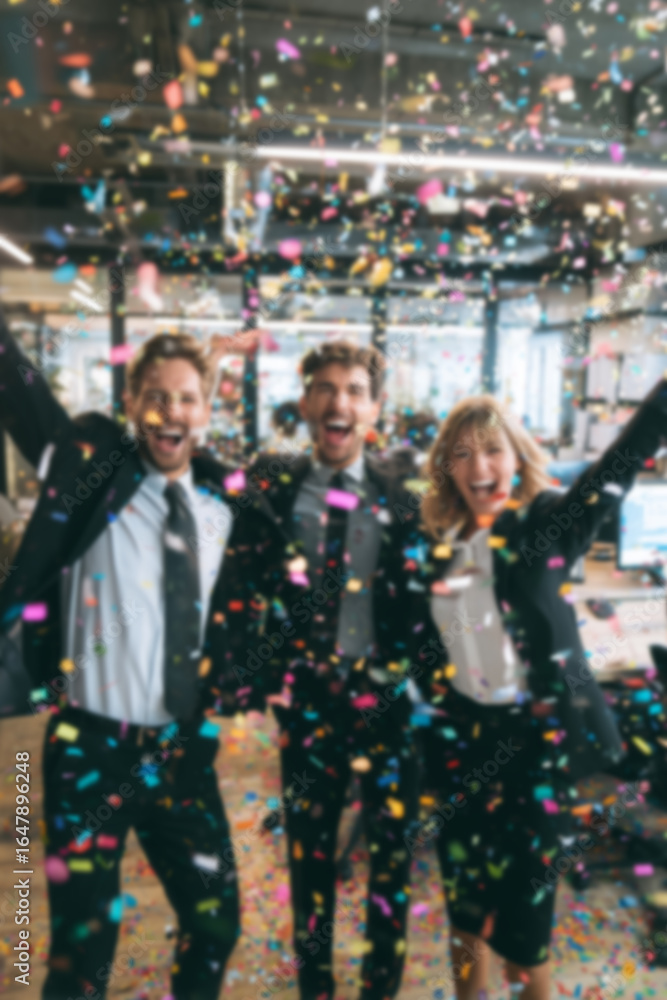 Fototapeta premium Blurred background of people in business suits celebrating in an office, throwing confetti and holding party streamers. Concept of corporate celebration, team success, and joyful workplace moments.