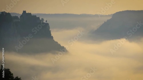 Castle in the mountains surrounded by fog during sunrise in saxon switzerland