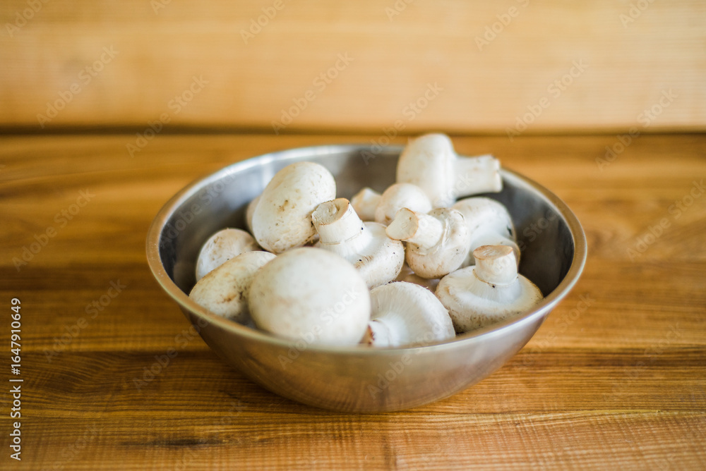 Fresh white mushrooms in a metal bowl on wooden background. Fresh white mushrooms in a metal bowl on wooden background.