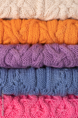 Abstract knitted background from set of multicolored knitted clothes stacked. Space for text. Knitting warm clothes, blankets and blankets. Concept of home needlework
