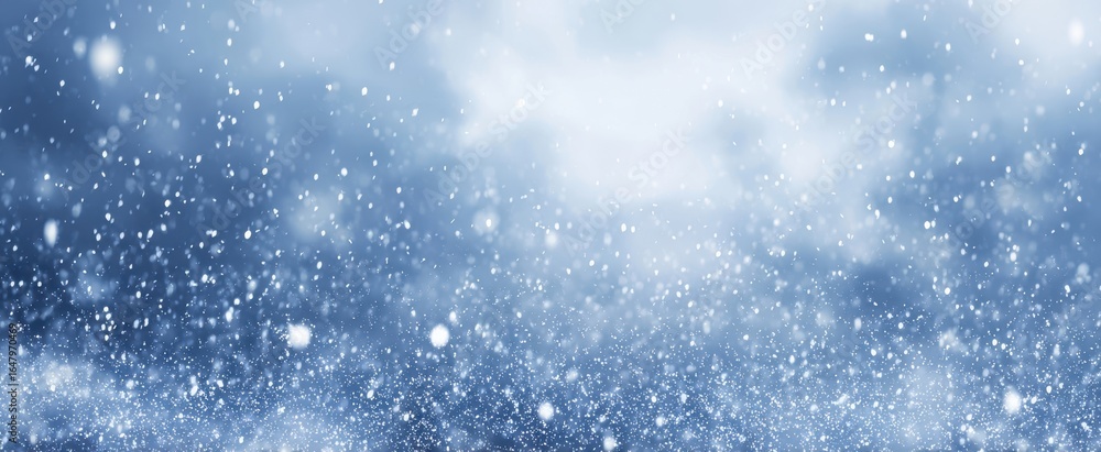 Obraz premium The Snowfall Over a Soft Blue Winter Background with Gentle Bokeh Light