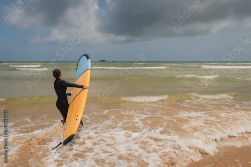 surfer on the beach or young woman going surfing with her board on the waves of tropical island