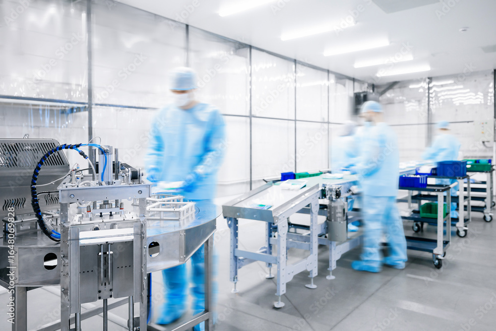 Fototapeta premium Medicine factory, sterile box production line for medical instruments and surgical kits. Workers in uniformed pack scalpels, clamps, tweezers and bandages on conveyor belt