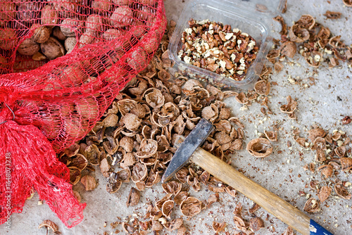 Organic walnuts, shelled walnuts with a hammer, old way of shelling walnuts, pile of walnuts with a shovel and a red bag of nuts
