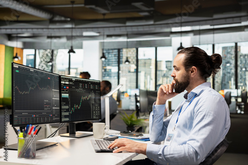 Trader in prop firm office analyzing market data and executing trades using trading software interface on PC. Stockbroker working for asset management company monitoring stock prices using computer