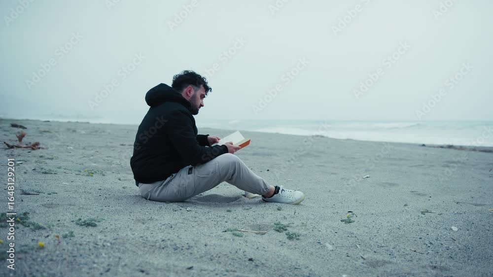 Sad Man Starts Reading A Book Sitting On The Sand In Winter Sad Man Starts Reading A Book Sitting On The Sand In Winter