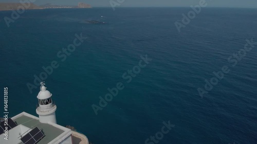 Aerial view of lighthouse with solar panels on coastline in Spain