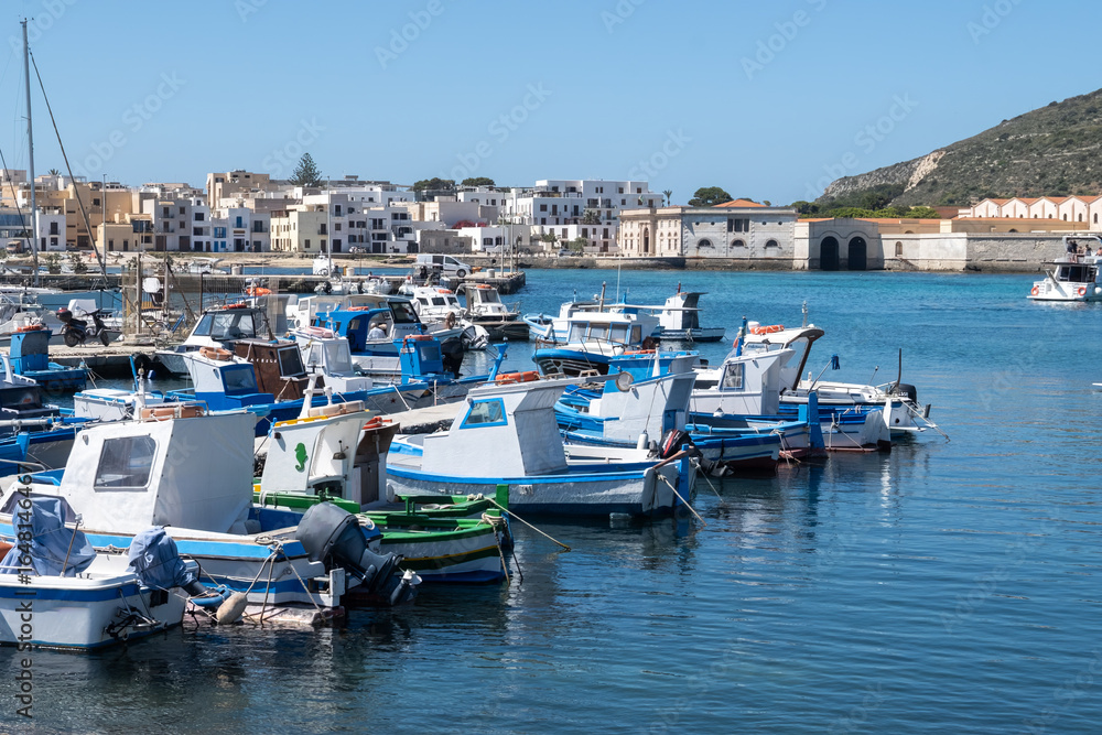 Obraz premium Little traditional colourful fishing boats in Favignana island's harbour, near Sicily, tourists destination, boat trip, Italy