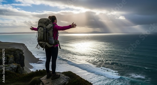 Woman Hiker Embracing Coastal Vista Dramatic Sky Sunlit Ocean Cliffside View.