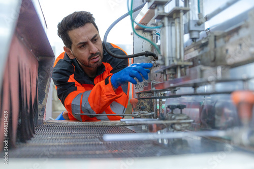Workers in safety gear inside a factory check equipment and products on production and transportation lines in a closely monitored, state-of-the-art food processing plant.