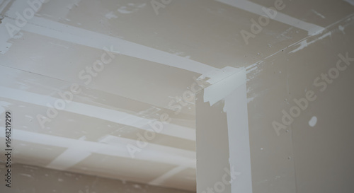 Unfinished drywall seams and joint compound on walls and ceiling during interior construction and renovation.