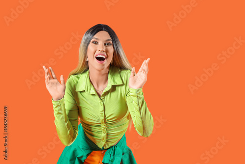 Beautiful young happy woman in wig on orange background