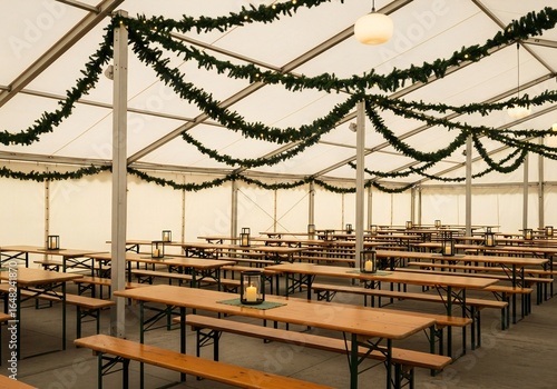 Oktoberfest Empty beer garden tent with wooden tables and benches decorated with festive garlands and lanterns