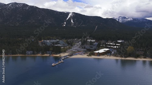 Riva Grill and Marina with sunshine and snow storm arriving over South Lake Tahoe looking toward Heavenly Valley on a cold May day with freezing rain Drone footage