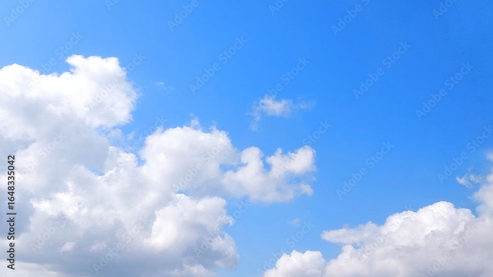 Clear blue sky with white clouds. Panoramic blue sky background with fluffy white cumulus clouds. Aerial view of cloudscape on sunny day. Clear blue sky with white clouds. Panoramic blue sky background with fluffy white cumulus clouds. Aerial view of cloudscape on sunny day.