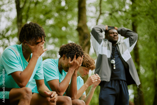 Valokuva Three teenage boys, including Black and Caucasian, sitting on bench covering fac