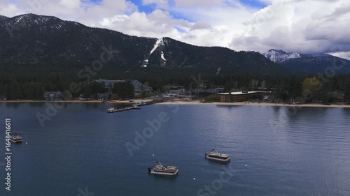 Riva Grill and Marina with sunshine and snow storm arriving over South Lake Tahoe looking toward Heavenly Valley on a cold May day with freezing rain Drone footage