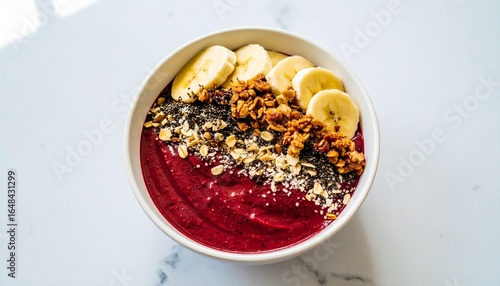 Bright and colorful acai bowl with bananas and granola on a white table, Delicious and healthy acai bowl with fruits and grains for a refreshing meal