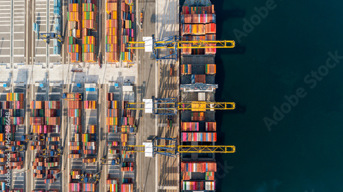 Top view of a large cargo ship loading and unloading containers at a deep-sea port. This aerial scene highlights global logistics, international trade, and maritime transportation hubs.