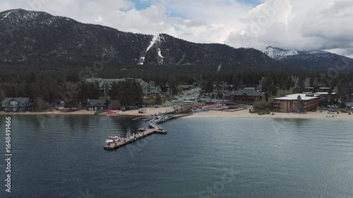 Riva Grill and Marina with sunshine and snow storm arriving over South Lake Tahoe looking toward Heavenly Valley on a cold May day with freezing rain Drone footage