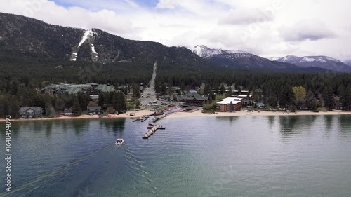 Riva Grill and Marina with sunshine and snow storm arriving over South Lake Tahoe looking toward Heavenly Valley on a cold May day with freezing rain Drone footage