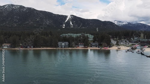 Riva Grill and Marina with sunshine and snow storm arriving over South Lake Tahoe looking toward Heavenly Valley on a cold May day with freezing rain Drone footage