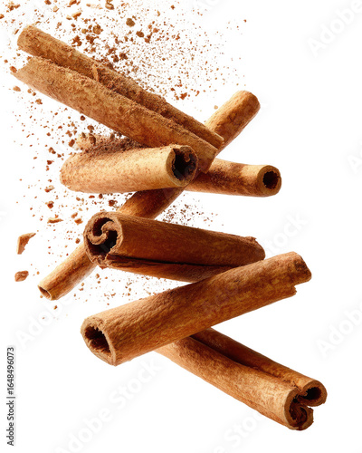 Cinnamon sticks, in motion, amidst a spray of ground cinnamon