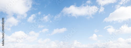 light blue sky background with fluffy fair weather clouds, panorama format