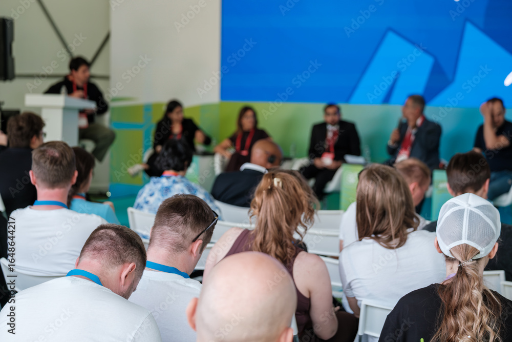 Obraz premium Panel discussion with attendees focused on business and innovation at a technology event.