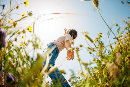 young and cheerful guy dances among the flowers. Handsome man dancing in nature. Summer mood. Happy young guy among blooming flowers, outdoors.