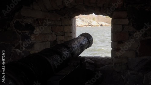 medieval cannon pointing from a loophole towards the sea