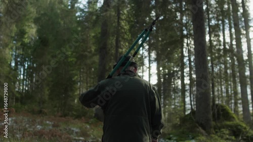 old man walking through a forest with shears