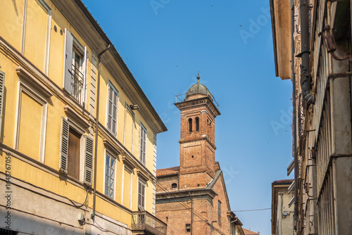 Wallpaper Mural Piacenza, Italy. The bell tower of a historic church is framed by narrow residential buildings on a sunny day in the city's old town Torontodigital.ca