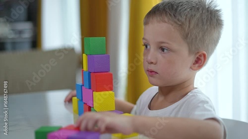 Child play at home with colorful blocks on table. child enjoying creative playtime indoors. Table play fosters child development. Home environment enhances imaginative play. Child hands engaged play.