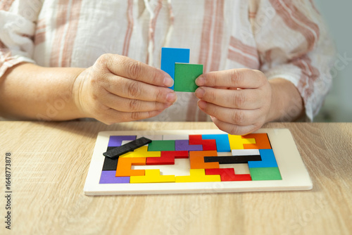 Obraz na plátně Mature female hands manipulate colorful wooden geometric shapes intellectual puz